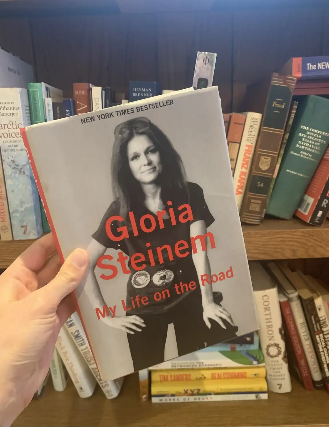 A hand holds up a copy of "My Life on the Road" by Gloria Steinem.