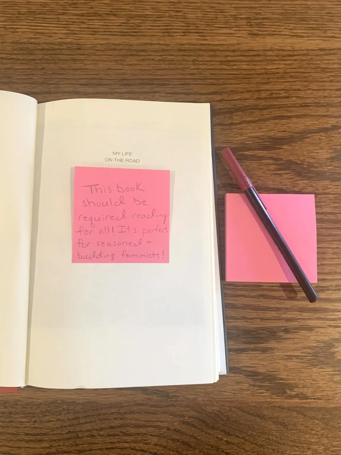 A pink sticky note on the inside cover of an open book.