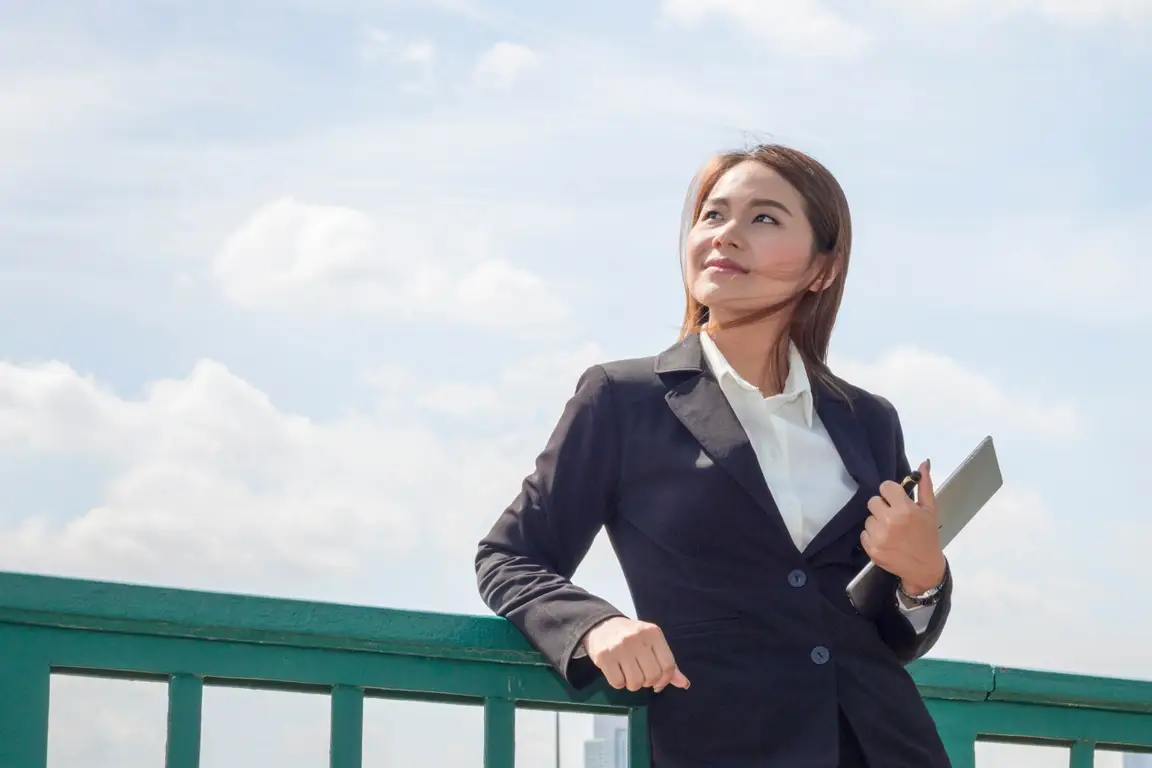 A young professional woman looking up into the sky.