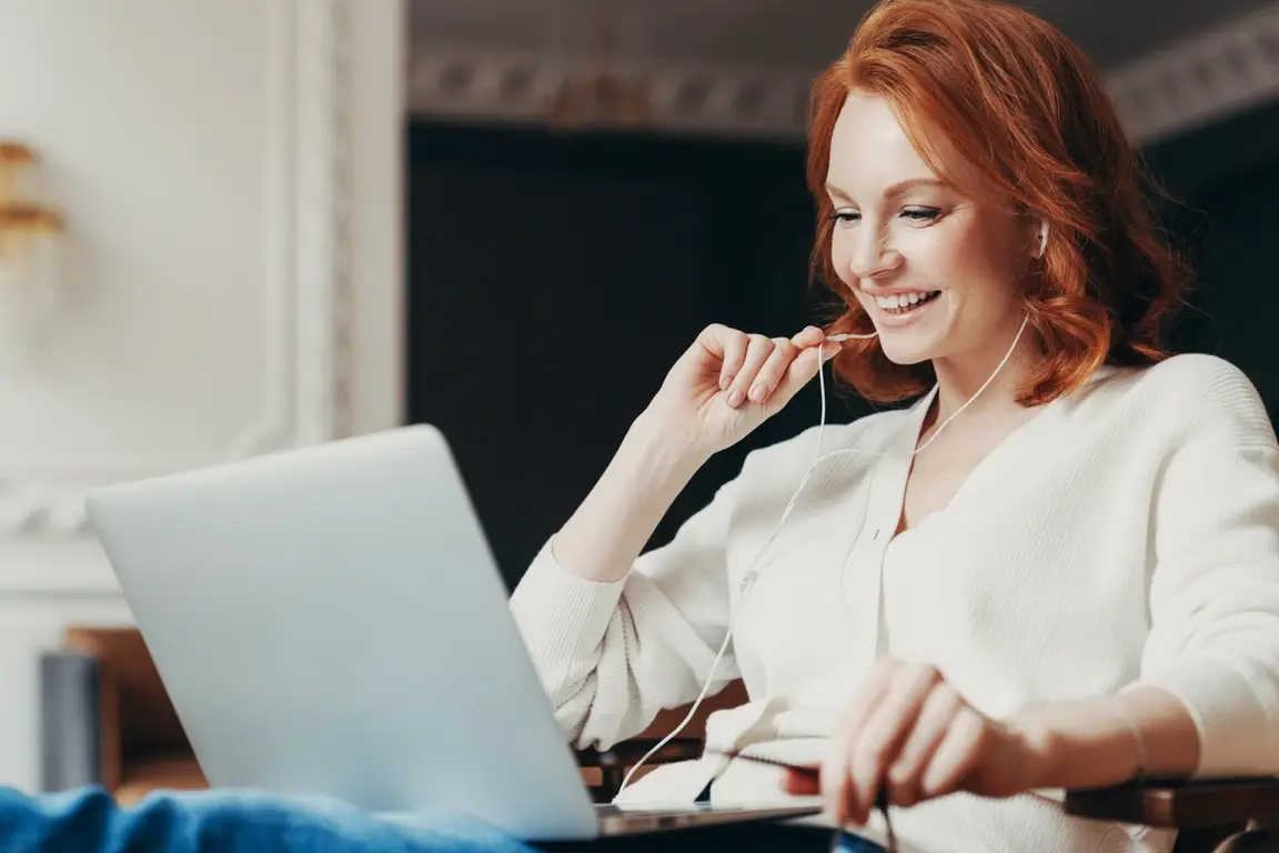 A young woman smiling at her laptop during an interview