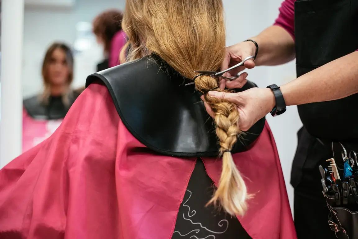 Hairstylist cutting woman's braid.