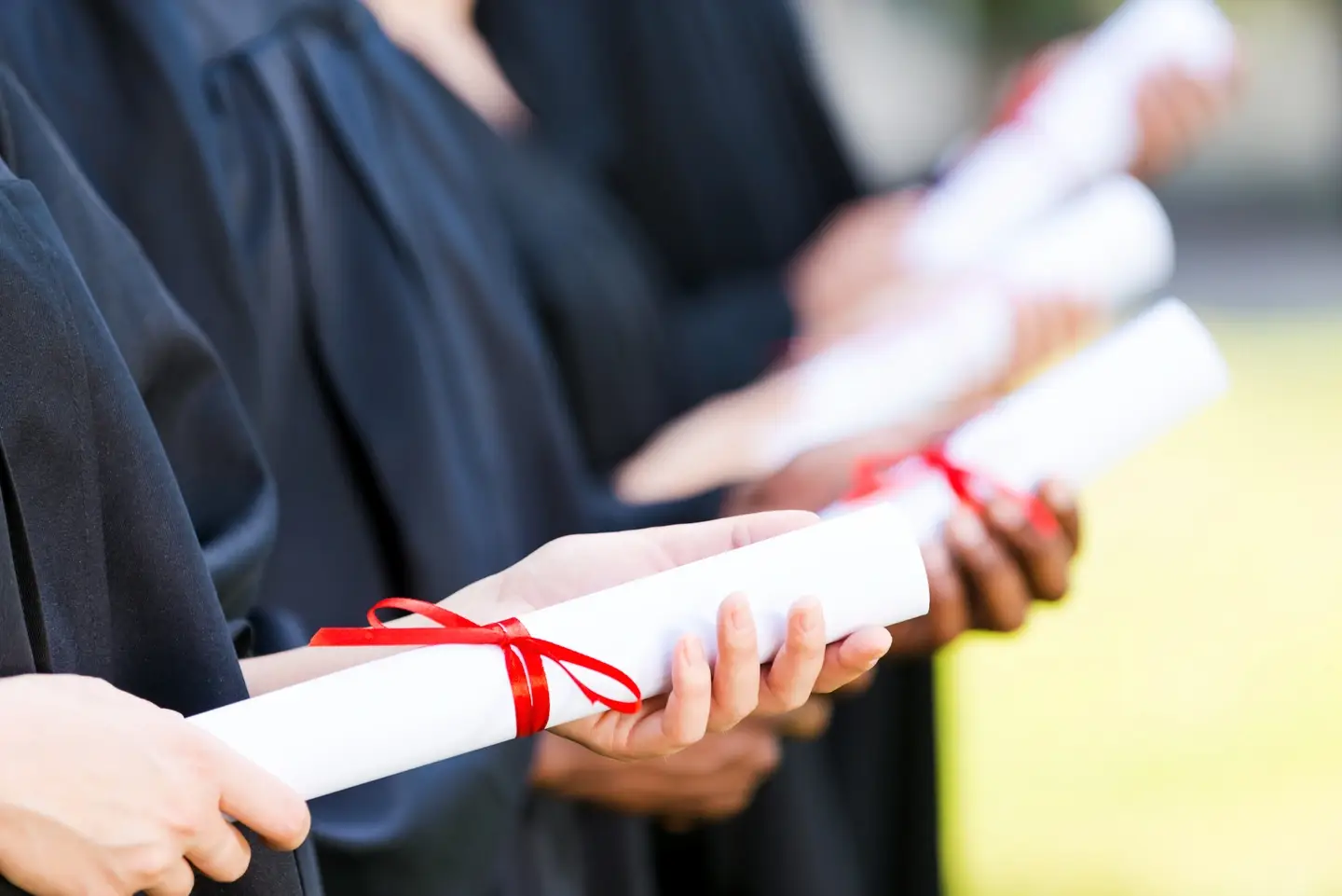 A photograph of grad students holding out diplomas.