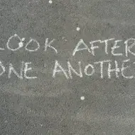 "Look after one another" written in chalk on concrete.