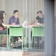 Group of multi-racial colleagues sit at desk and discuss duties as board members.