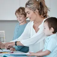 A mother working at a computer with her children on either side.