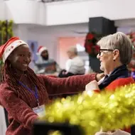 Young Black woman volunteers at a free store helping people find clothing during holiday volunteering.