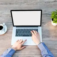 Pessoa usando um computador com uma xícara de café ao lado
