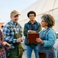 Nonprofit manager at a greenhouse or farm speaks to co-workers to build positive relationships.