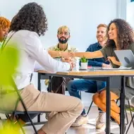 Group of multiracial people sit at a long desk in their office space to hire a new nonprofit candidate.