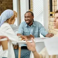 Two co-workers chat happily while sitting outside at office