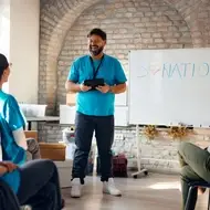 Happy mature coordinator talking to group of volunteers on a meeting at charity center.