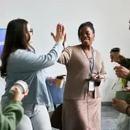 Co-workers with no college degree gathering in office space and high-fiving