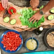 Grupo de personas cocinando sobre una tabla llena de ingredientes.