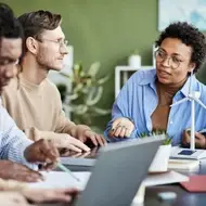 Group of multiracial co-workers gather around a table during a meeting at their new nonprofit job.