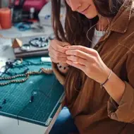 Mujer elaborando una pieza de bisutería en su taller.