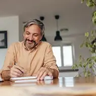 Man writes in professional journal at home.