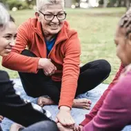 Multiracial group of women stacking hands together outside, symbolizing unity and teamwork.