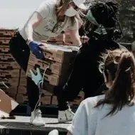 Foto de 3 pessoas ajudando a descarregar materiais de um caminhão.