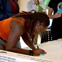 A young adult fills out a sticky note on a table