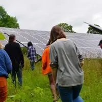 A group of people of various ages walks past solar panels