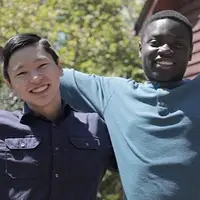 Zak from Kyrgyzstan and Meder from Ghana stretch their arms open and pose with big smiles in North Carolina, USA