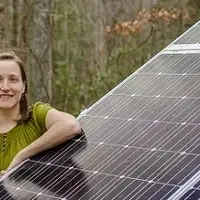 A man and a woman stand next to a slanted solar panel