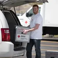 Man loading blood transportation container into Red Cross van