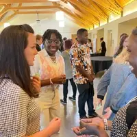 Two students listen as an adult asks them questions in a crowded room.