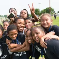 group of BIPOC children in America SCORES uniform on the side of a soccer field