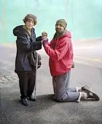 Two people, one kneeling, holding hands.