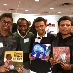 3 boys pose with their teacher and their books