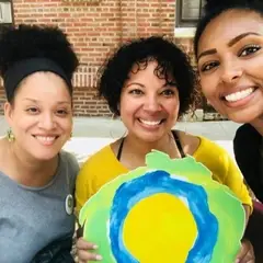 Three women smiling with the Idealist logo between them.