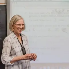 A teacher stands by a SMARTBoard and smiles at her students.