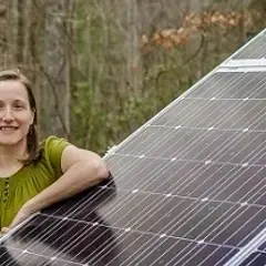 A man and a woman stand next to a slanted solar panel