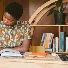 A Black person sits reading.