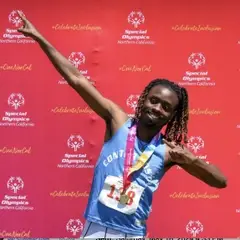 An athlete from Special Olympics Northern California proudly stands in front of the winners podium, holding their medal with a bright smile, embodying determination and achievement.