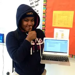 a young writer poses with her laptop, showing her completed work, she is giving a thumbs up