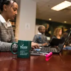 Student typing on computer at the John Burton Library at School for Conflict Analysis and Resolution.