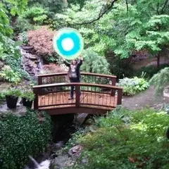 A woman on a bridge holds up the Idealist logo.