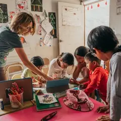 A group of children is studying English supported by their volunteer teacher