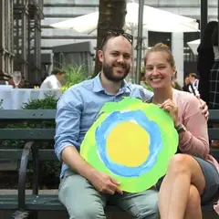 A couple at a bench with the Idealist logo between them.