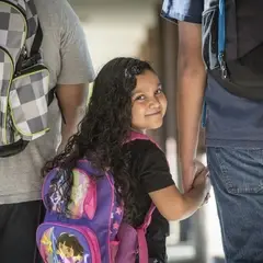 child with backpack looking backwards