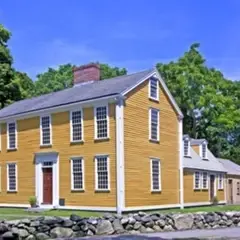 Yellow, colonial-era, two-story building with additions at back