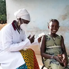 A healthcare professional helping a child at home in a village