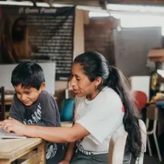 A kid reading a book with his mother