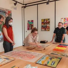 A group of people around a table of books and printed objects. One person points at an old book.