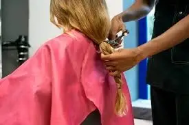 Peluquero cortando una trenza de pelo a una mujer.