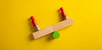 Photograph of red building blocks finding balance on a yellow background.
