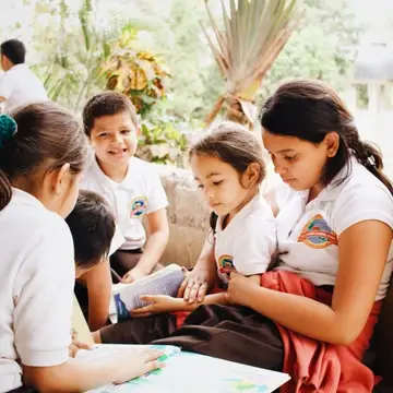 A group of reading buddies huddled around a book at San Jeronimo