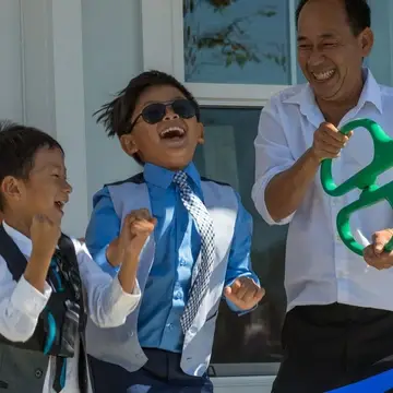 Woman, two small boys and man celebrate after cutting ribbon on home